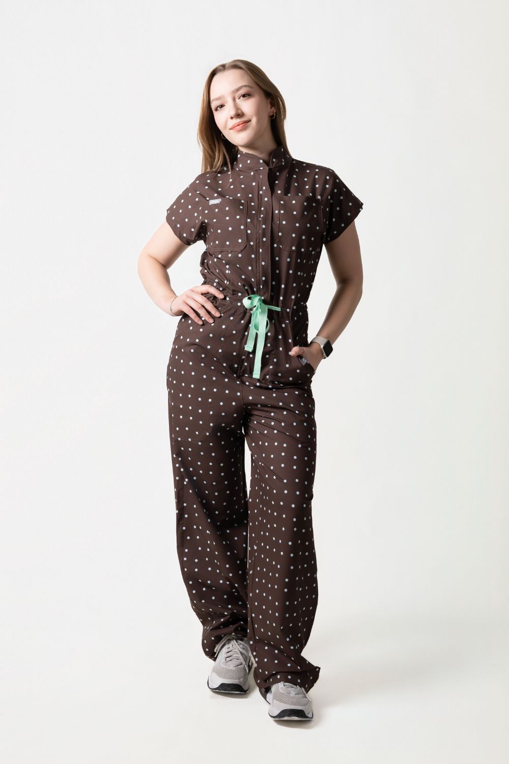Rebel Jumpsuit Cocoa de Jogs Scrubs — enterizo médico antifluidos color chocolate con polka dots blancos, vista frontal completa