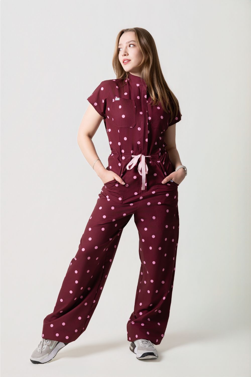 Rebel Jumpsuit Cherry de Jogs Scrubs — enterizo médico antifluidos color vino con polka dots rosa pastel, vista frontal completa